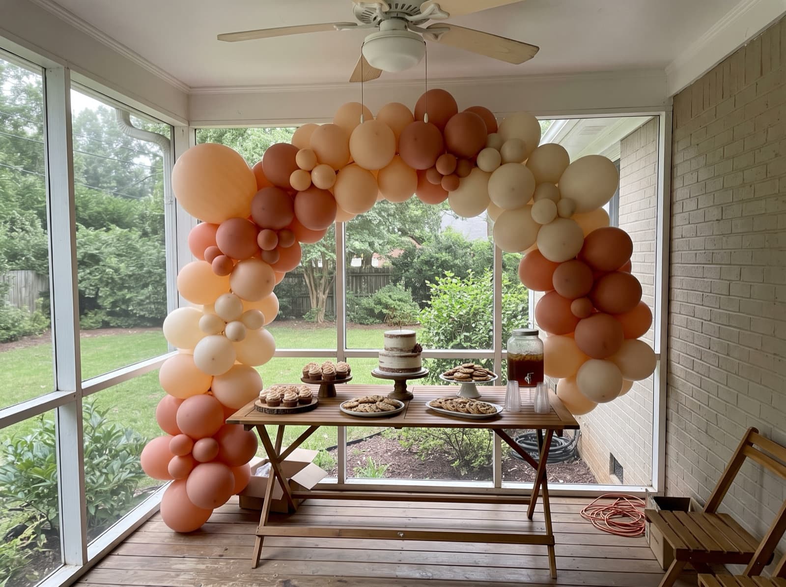 Organic balloon arch in peach, terracotta and cream over a dessert table at an Atlanta birthday party