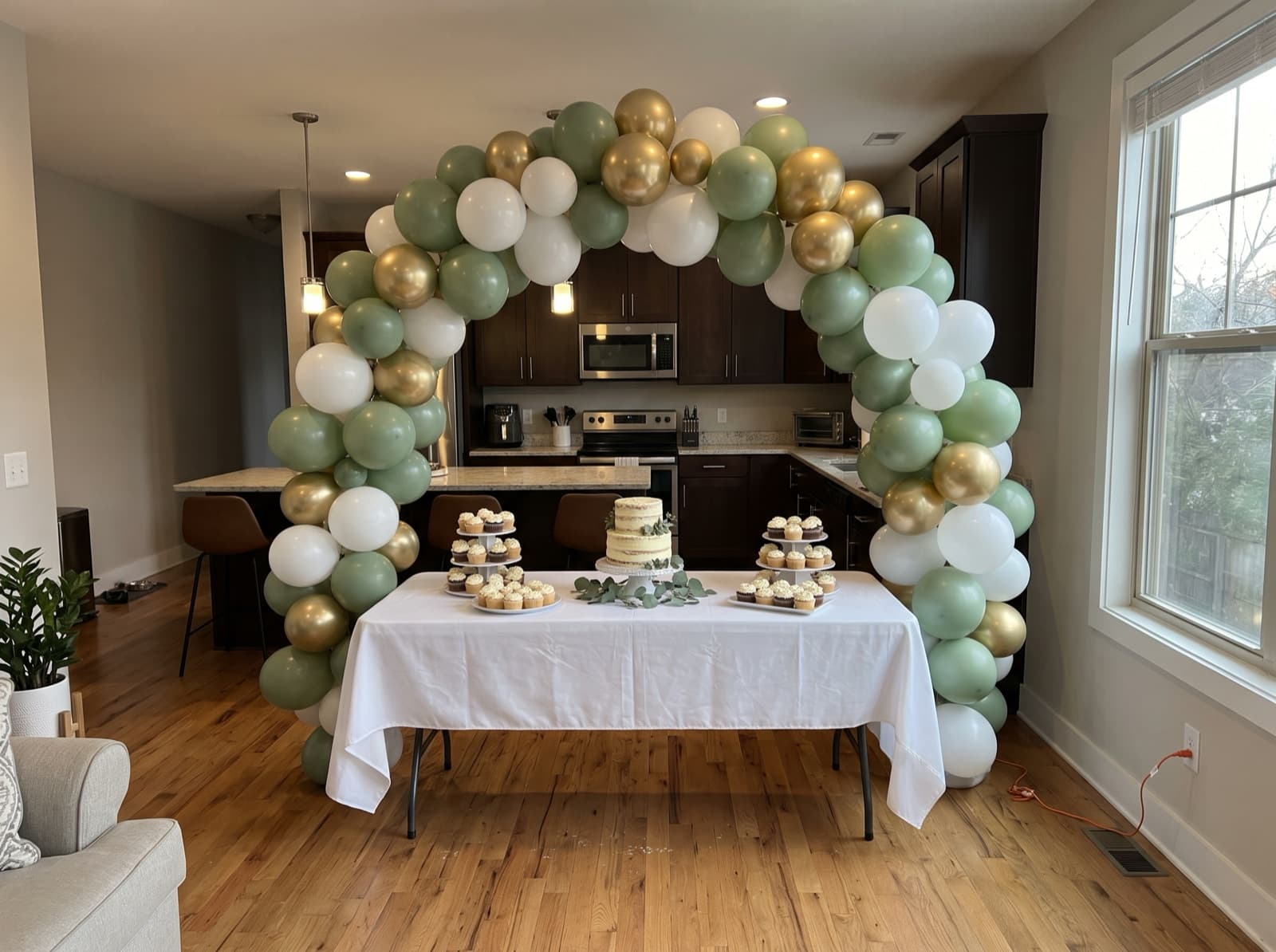 Organic balloon arch in sage, white and gold over a dessert table